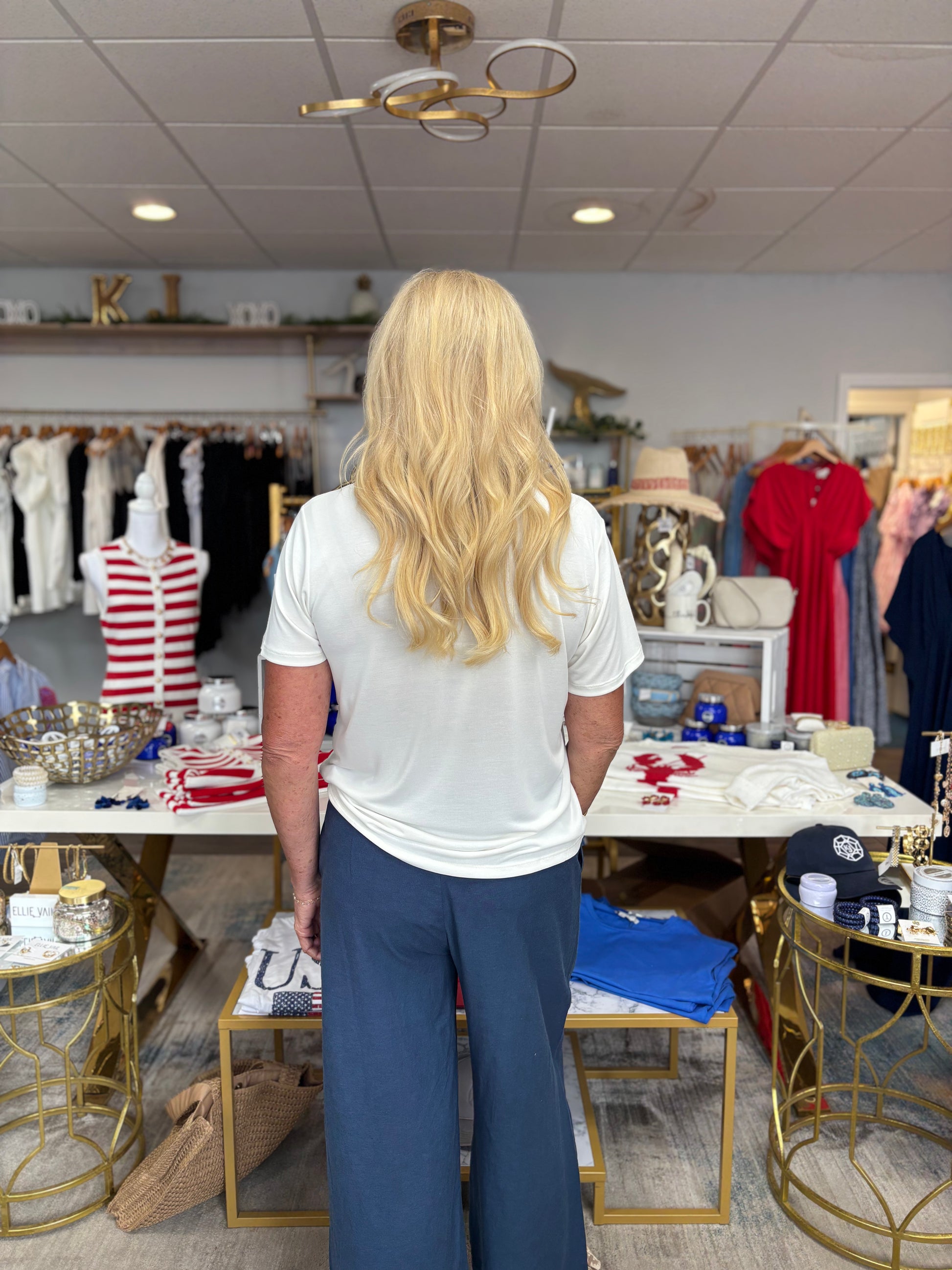 Person standing in a store with tables and clothing racks.
