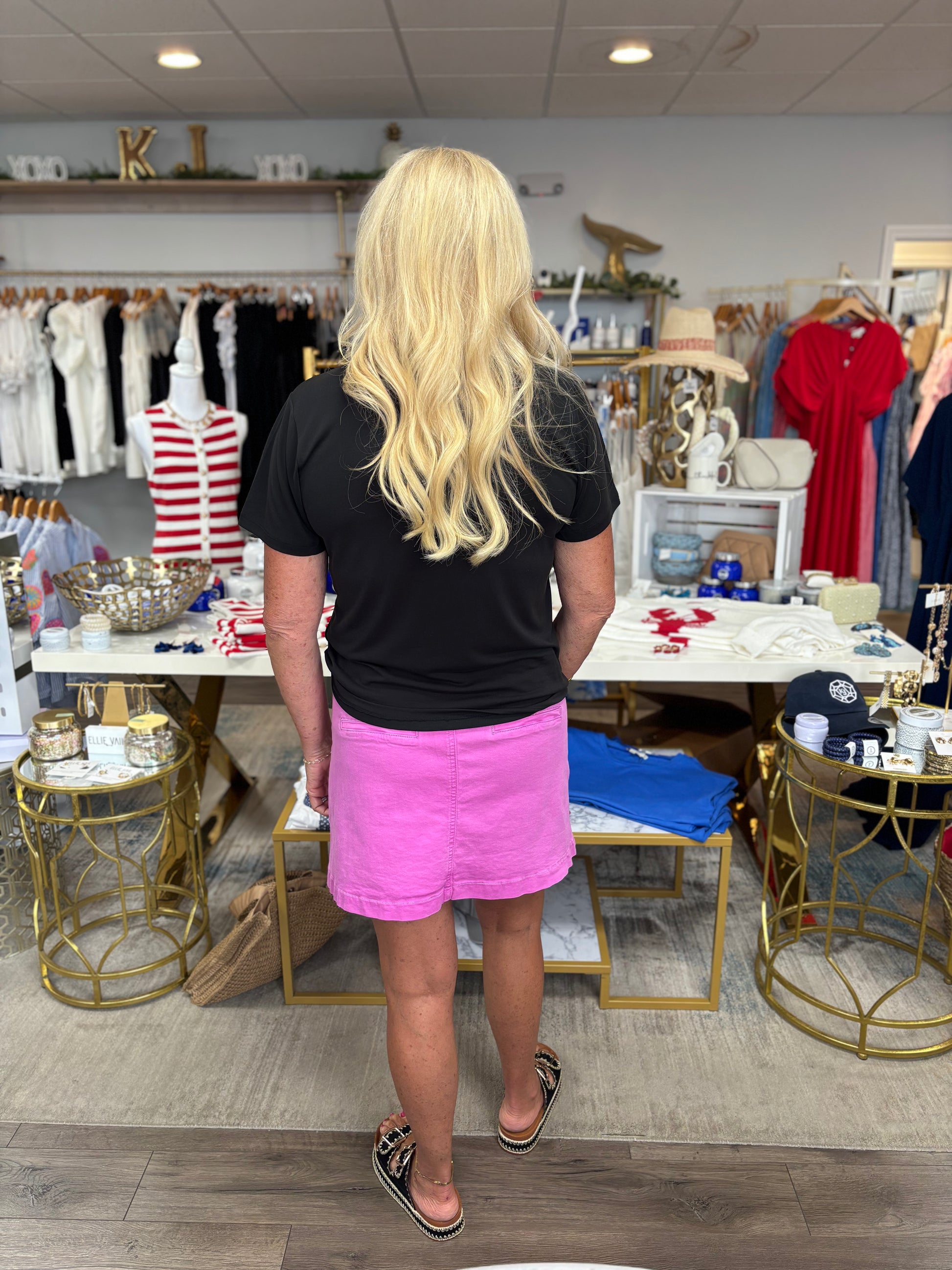 Person wearing a black t-shirt and pink skirt in a store setting