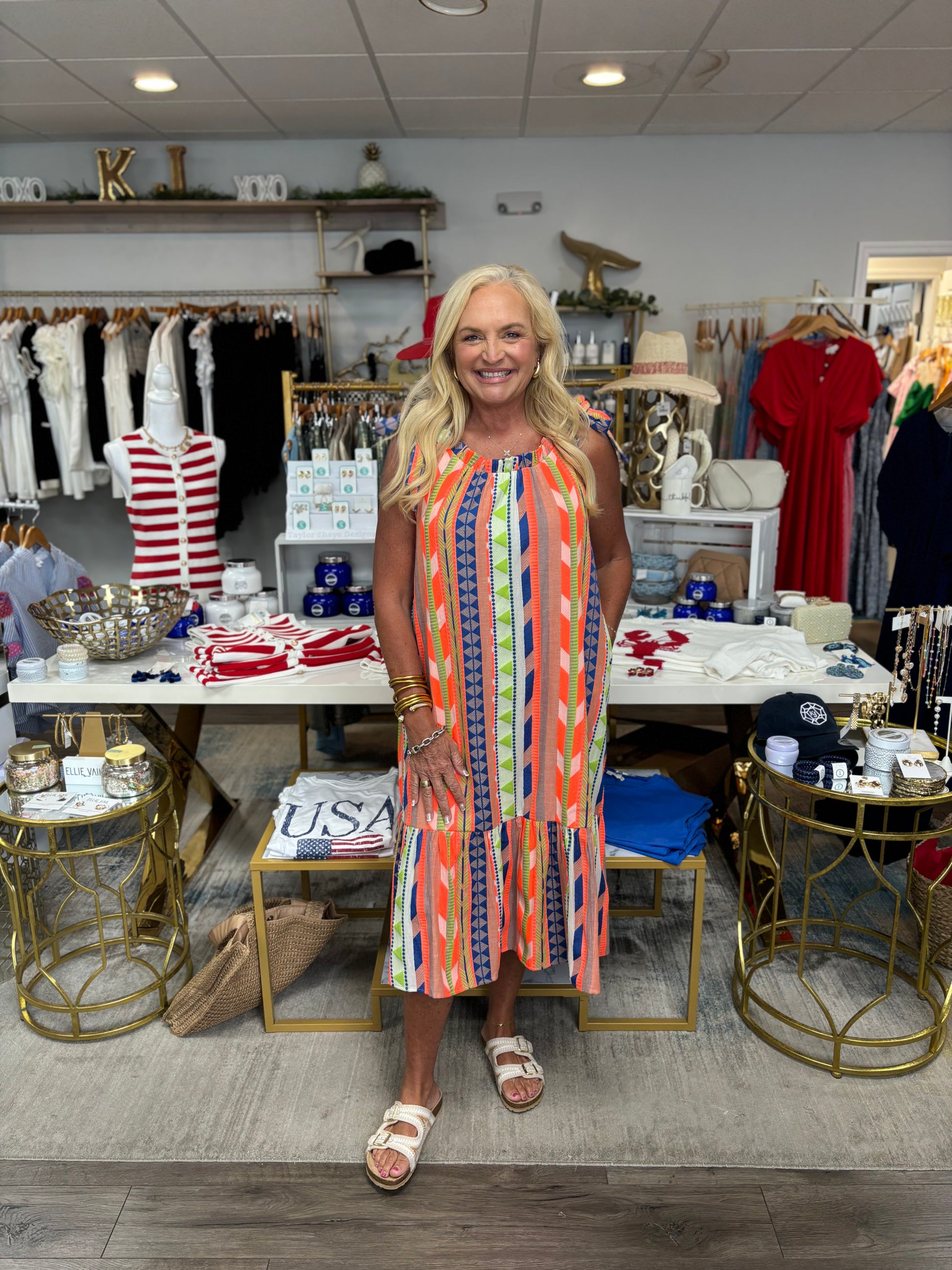 Woman in a colorful dress standing in a store with various items on display.