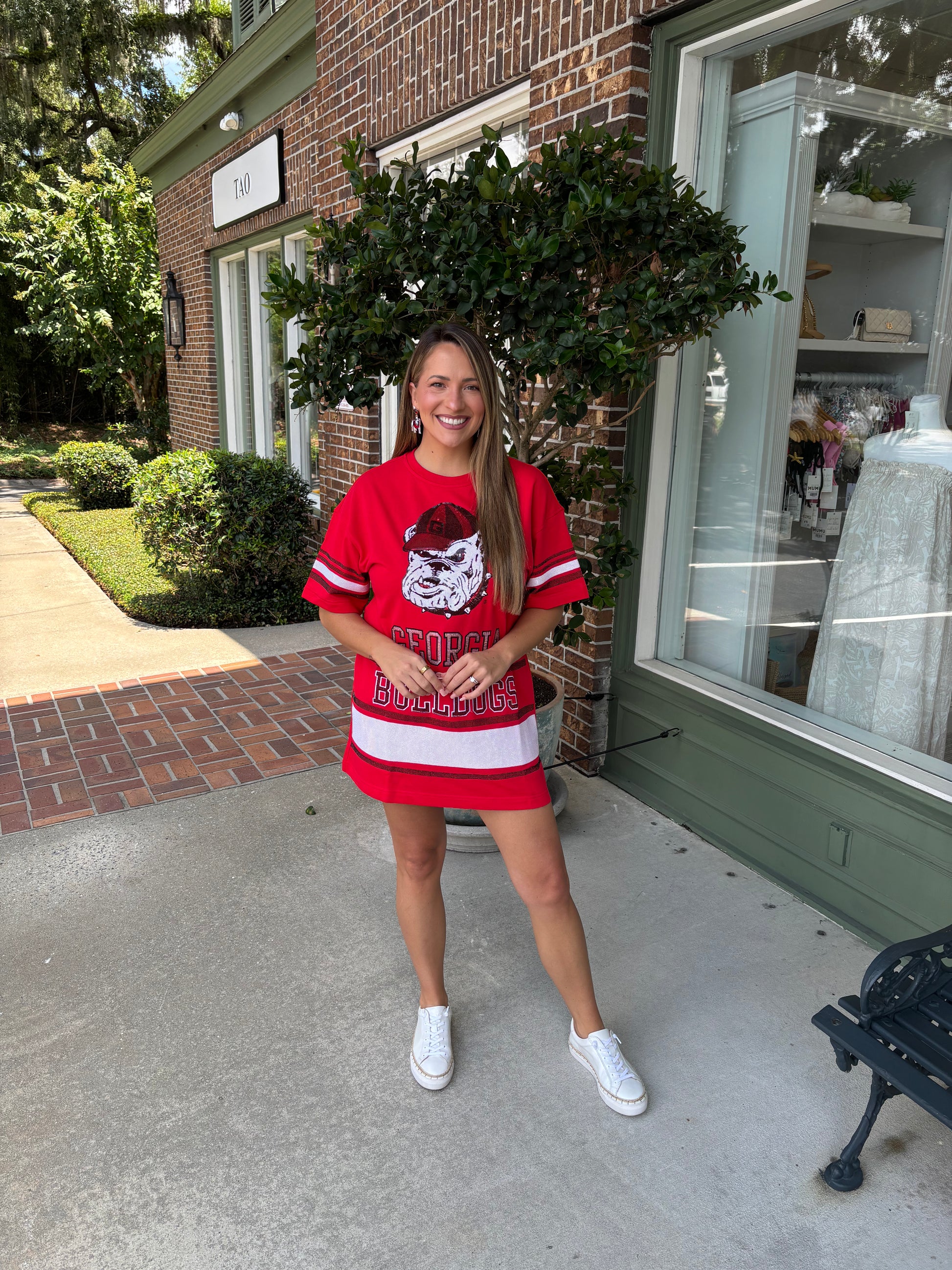 Woman wearing a red dress with a graphic design standing in front of a brick building.