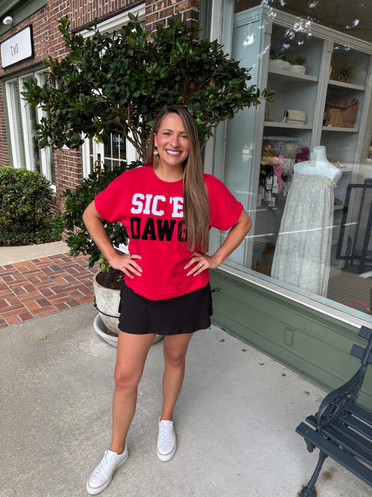 Woman wearing a red 'SIC EM DAWG' t-shirt standing outside a store.