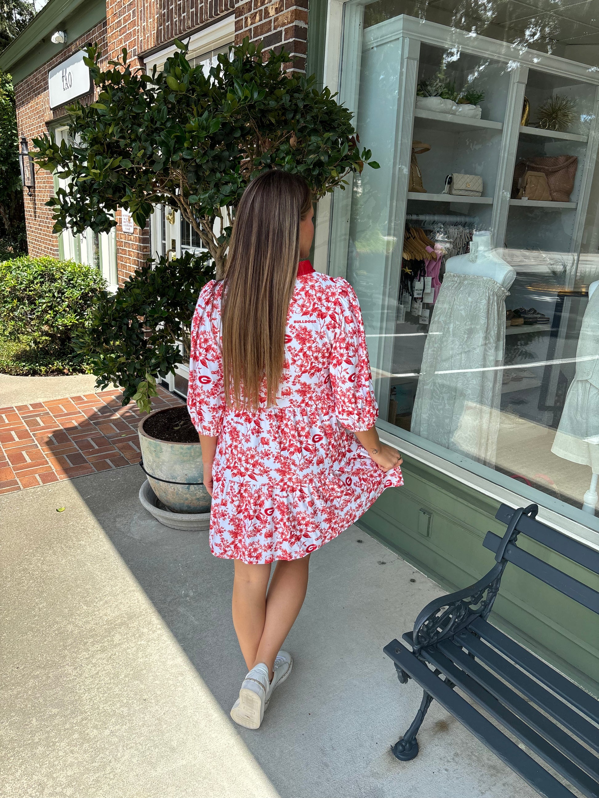 Woman in a red floral dress walking past a store window