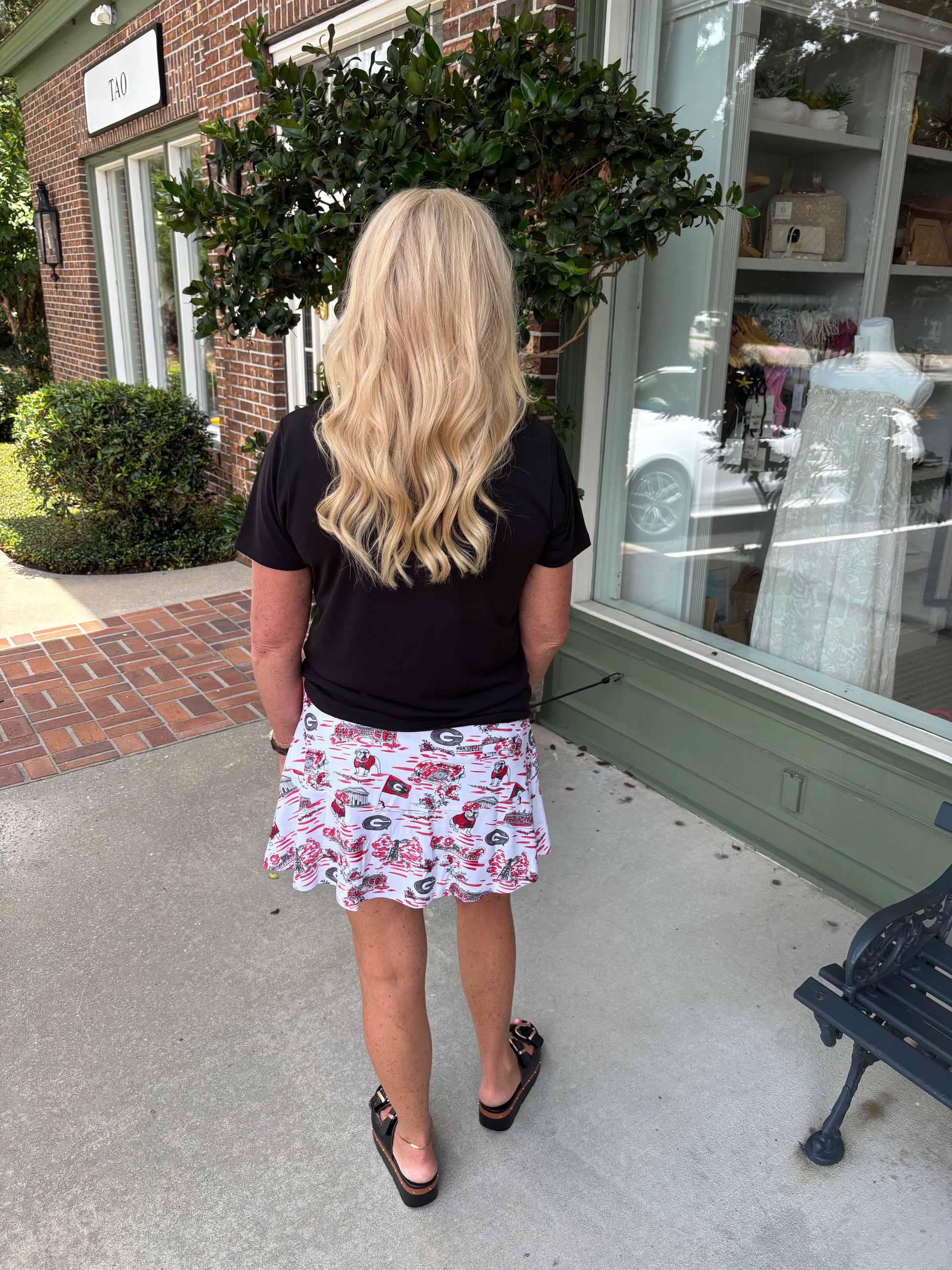 Woman standing outside a store with a floral skirt and black top