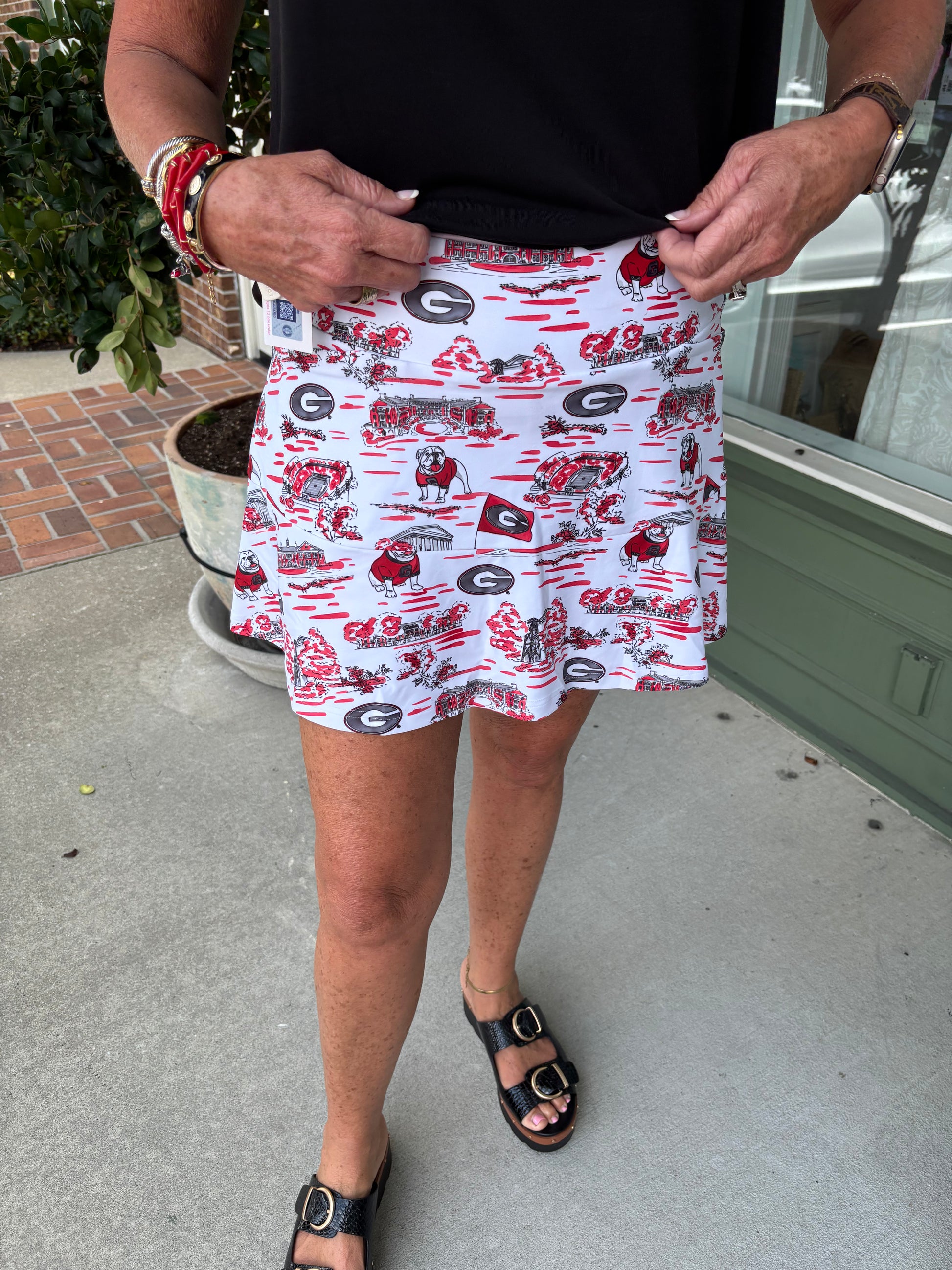 Person wearing a white skirt with red and black patterns, standing on a concrete surface.