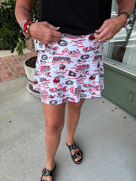 Person wearing a white skirt with red and black patterns, standing on a concrete surface.