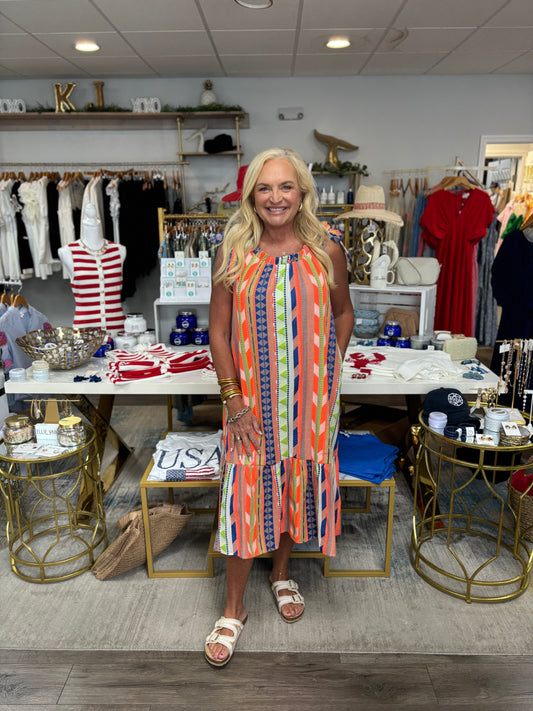 Woman in a colorful dress standing in a store with various items on display.