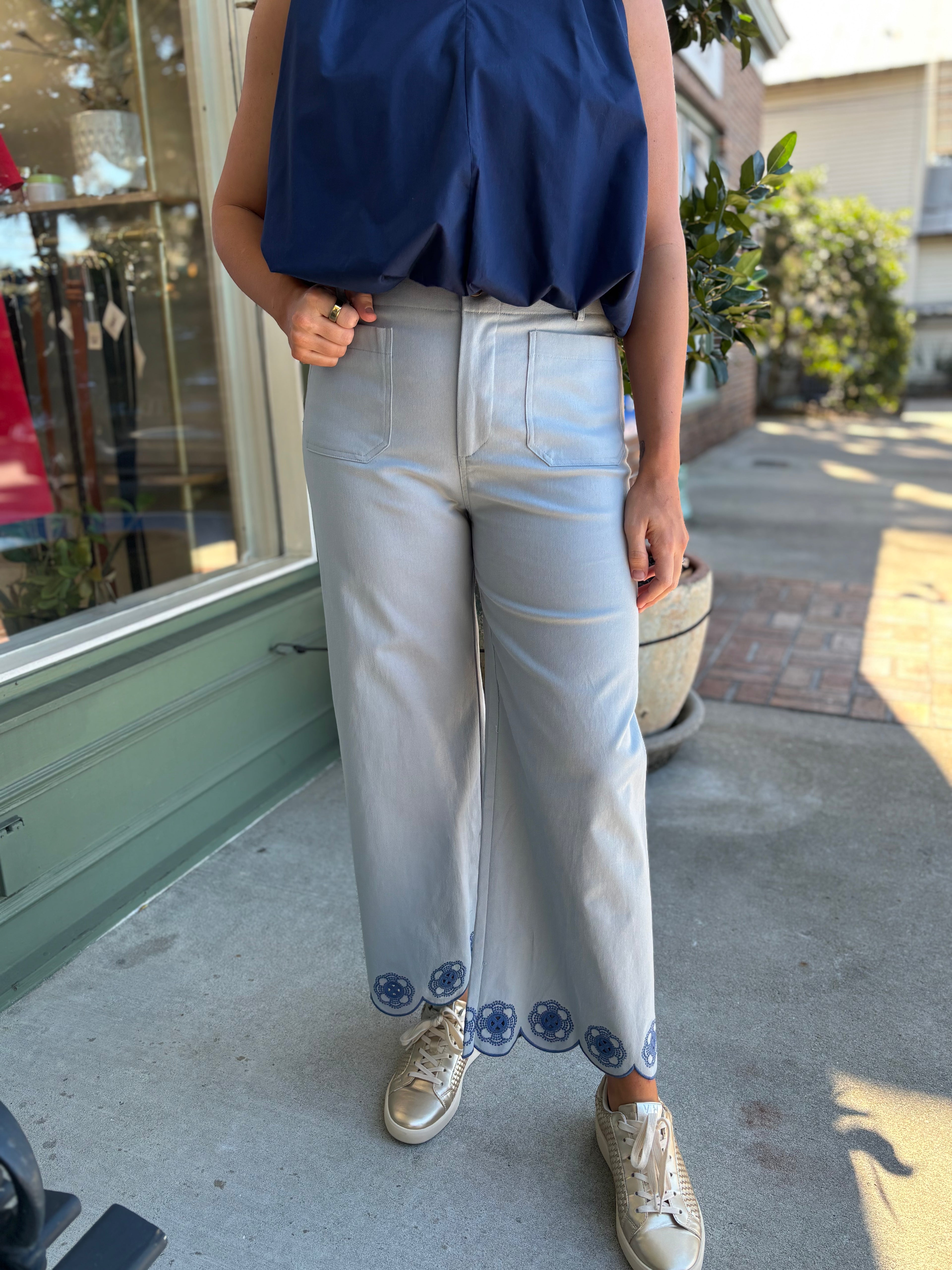 Light blue wide-leg pants with decorative hem on a beige background