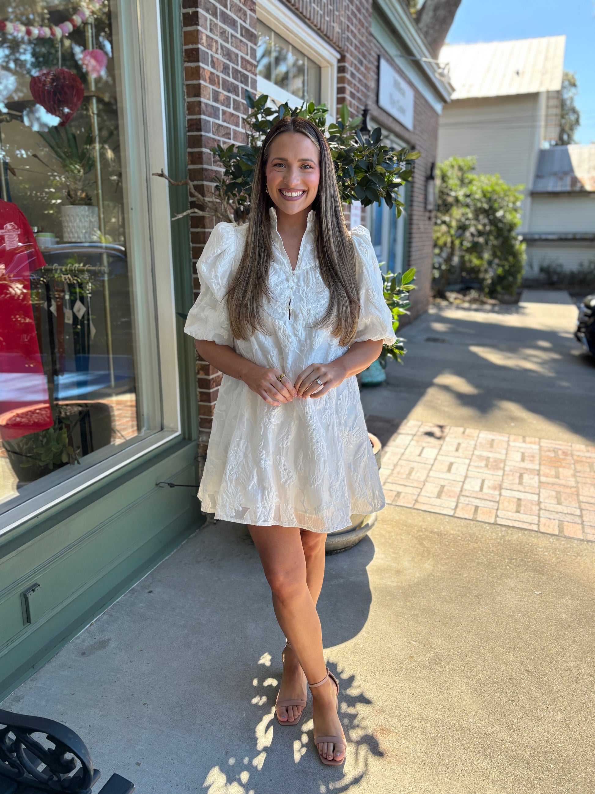 Brocade ivory dress with ruffle neckline, puff sleeves and exposed button details styled for brides 