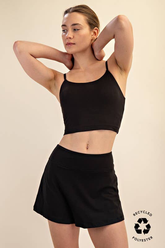 Woman wearing a black sports bra and shorts on a beige background with 'Recycled Polyester' label.
